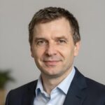 Портрет уверенного российского бизнесмена с дружелюбным взглядом на нейтральном фоне для сайта Альт ДФК